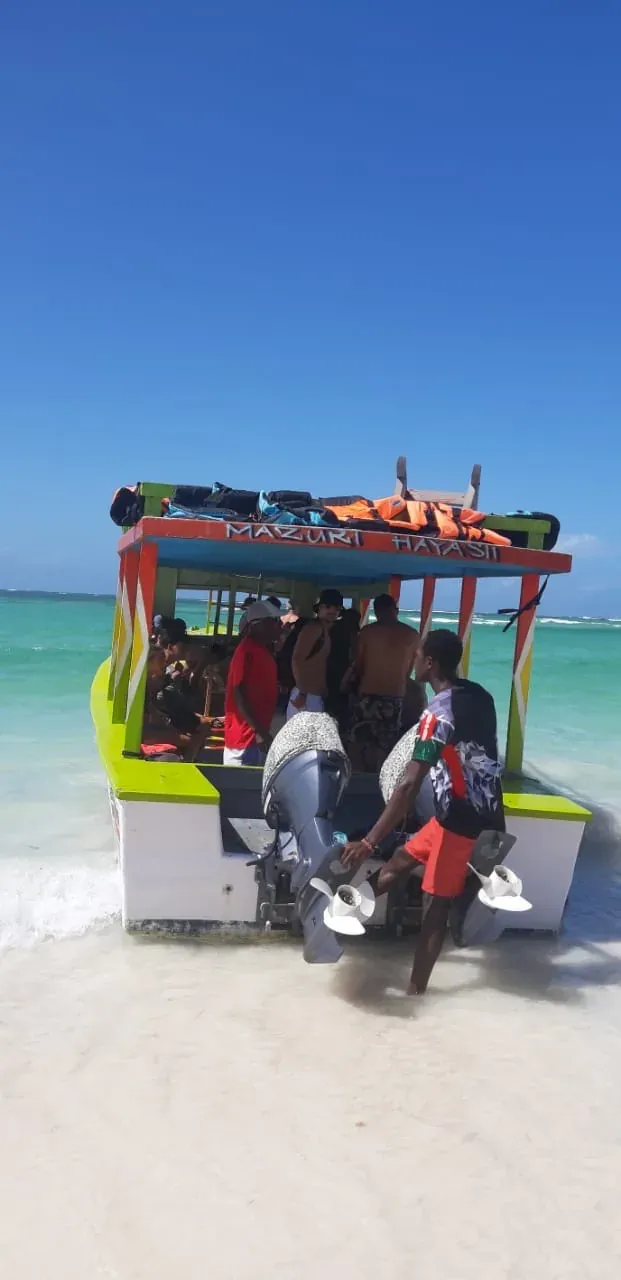The colourful excursion boat moored on the sandbank, guests aboard and turquoise water all around.
